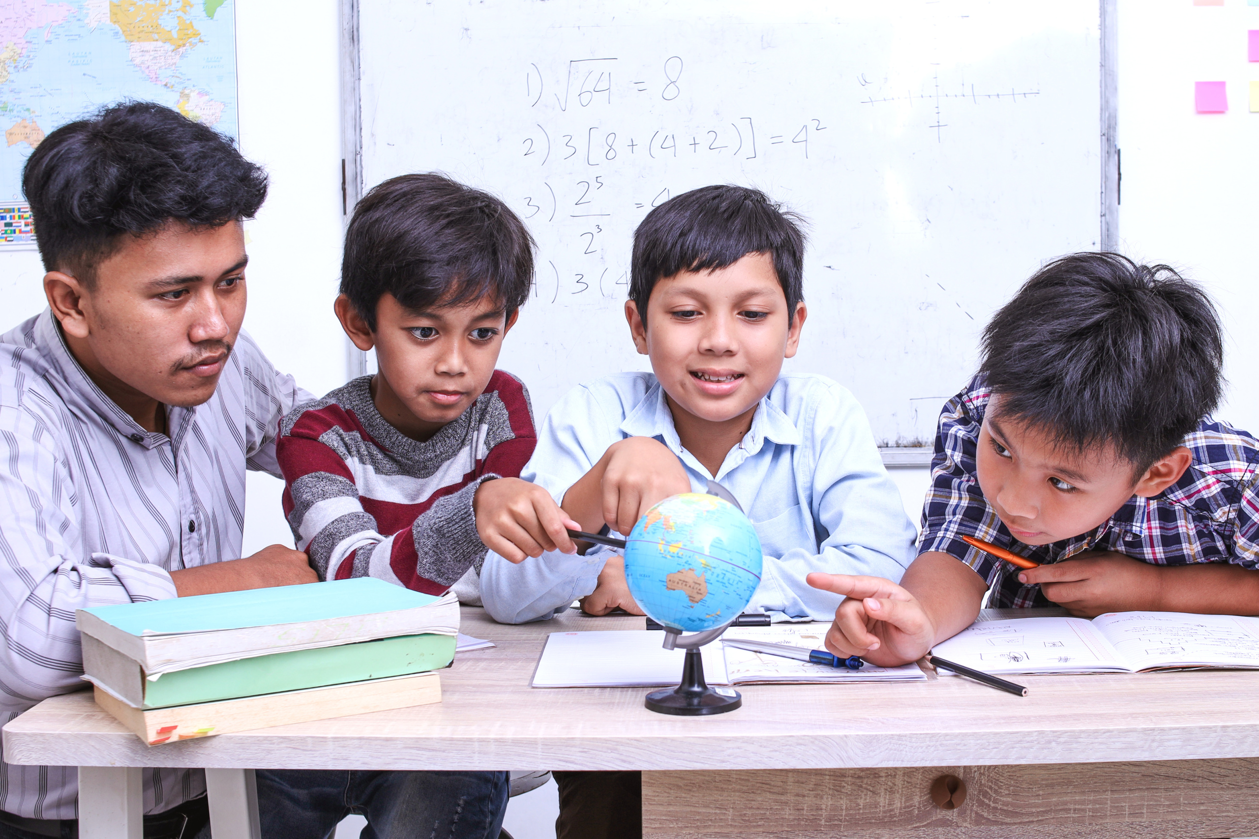 Teacher using a globe with diverse group of students